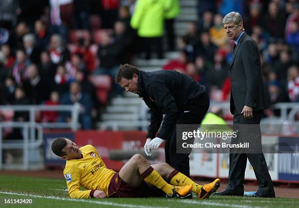 Arsenal Manager Arsene Wenger watches closley as Jack Wilshere of Arsenal is treated on the pitch for an injury after a challenge with Titus Bramble...