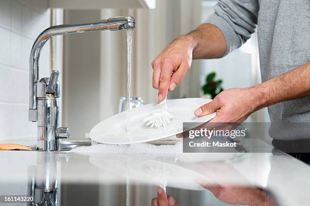 man cleaning plate - sink foto e immagini stock