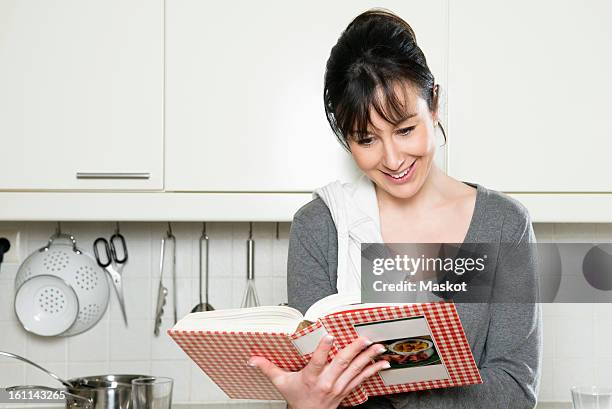 woman reading cookbook - cookbook stock pictures, royalty-free photos & images