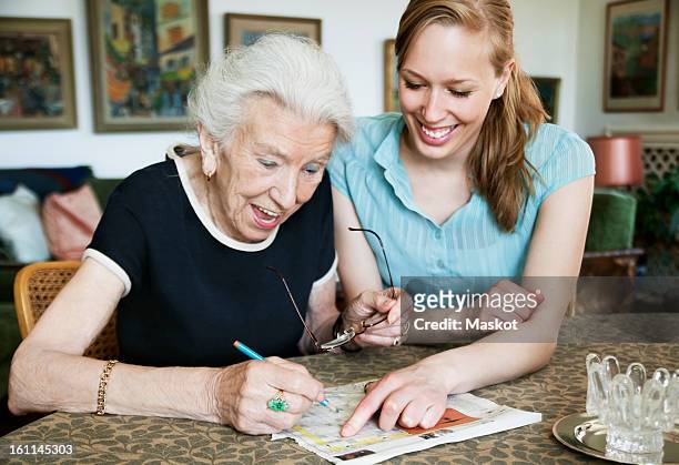 happy women solving crosswords - happy old women stockfoto's en -beelden