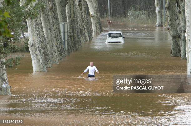 Man walks through a flooded road after his car suffered a breakdown, following heavy rain over the region, 20 October 2006 in Pezenas, southwestern...
