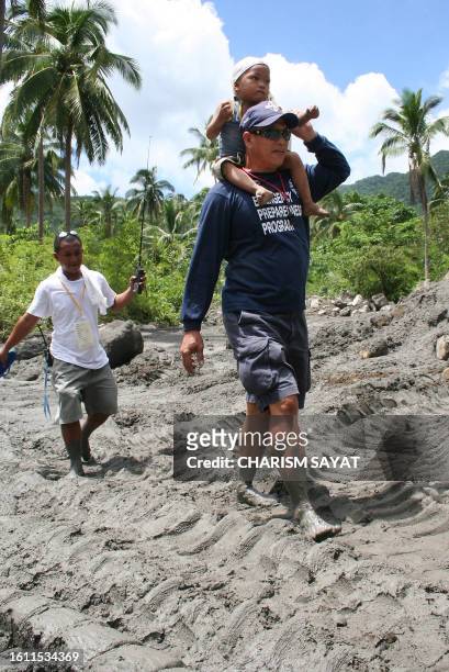 Members of the provincial rescue team walking barefoot on volcanic ash evacuate a boy from the danger zone in the village of Cogon, in Sorsogon...