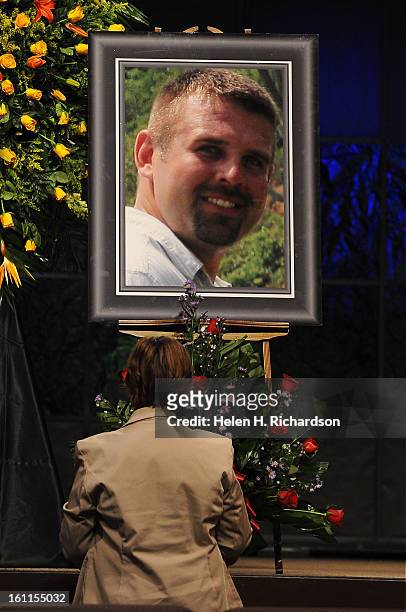 Cynthia Young takes a moment to herself in front of a portrait of David after the service to remember their son in law David Hartley. Despite having...