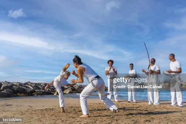 group of six capoeira players at beach - style musical photos et images de collection