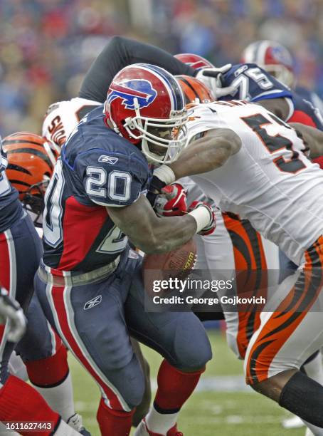 Travis Henry of the Buffalo Bills fumbles the football as he is hit by Kevin Hardy of the Cincinnati Bengals during a game at Ralph Wilson Stadium on...