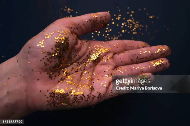 bright golden sequins on the hand. - draft after party stock pictures, royalty-free photos & images