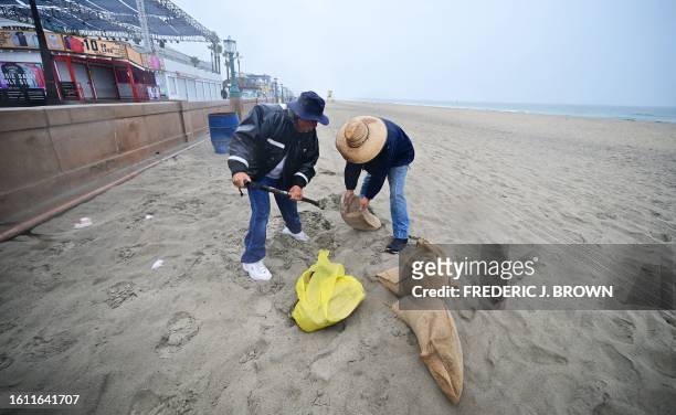 People fill bags with sand in preparation for rains from Tropical Storm Hilary, at Mission Bay Beach in San Diego, California, on August 20, 2023....
