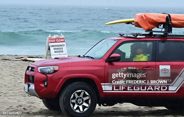 Sign instructs people to stay clear of the water as lifeguards patrol Mission Bay Beach in San Diego, California, on August 20 in preparation for...