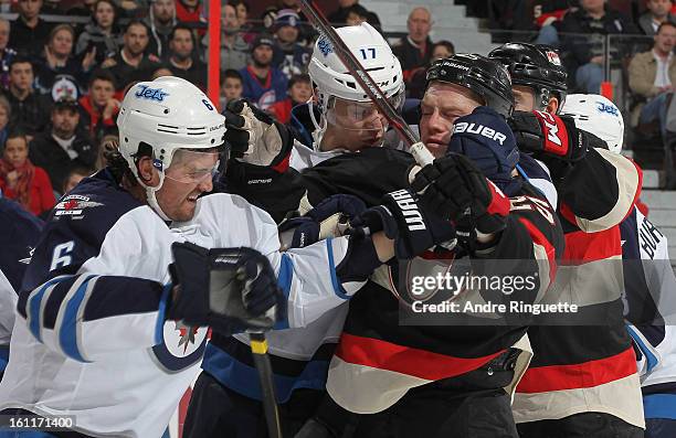 Chris Neil of the Ottawa Senators is pushed away from the crease after a whistle by Ron Hainsey and James Wright of the Winnipeg Jets on February 9,...