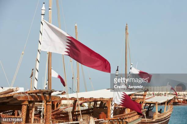 qatari flags on traditional dhows - qatar port stock-fotos und bilder