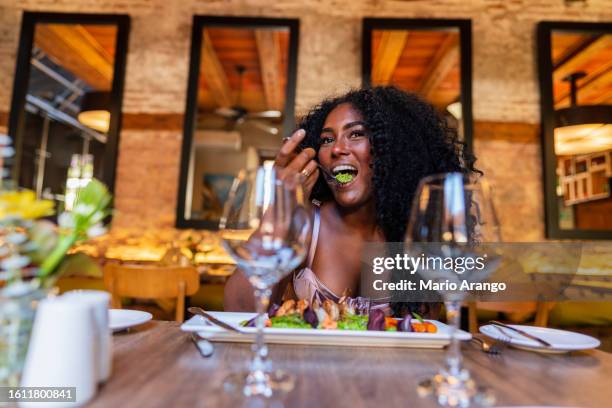 afro tourist sitting in the restaurant enjoying a delicious meal - caribbean culture stock pictures, royalty-free photos & images