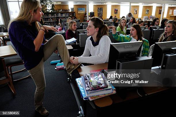 Sophomore Missy Franklin ties Katie Bell's shoe while working on a research paper for their Honors World History class in the library at Regis Jesuit...