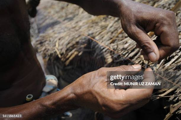 Displaced Bangladeshi villagers make fishing nets as they take shelter beside the street on the outskirts of Khulna some 400 kms from Dhaka on June...