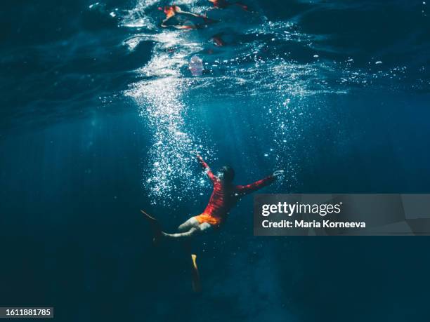 a man with fins and a snorkel dives underwater. - free diving stock pictures, royalty-free photos & images