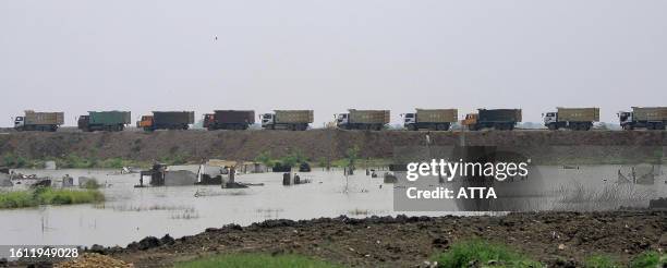 By Alvin Darlanika Soedarjo Trucks line up carrying concrete to dike mud of Lapindo's mud volcano as used to be people's houses are inundated in...