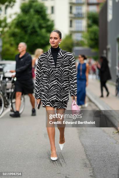 Guest wears large pearl earrings, a black wool turtleneck pullover, a black and white zebra print pattern oversized blazer jacket, a matching black...