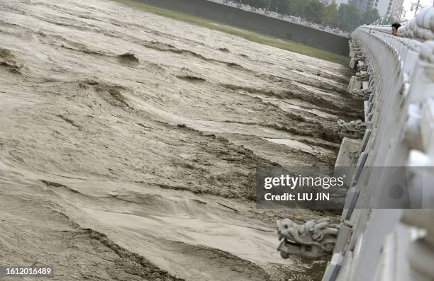 Man watches the flood waters in the Fu Jiang River in Mianyang city, flowing from the Tangjiashan quake lake after a controlled drainage operation in...