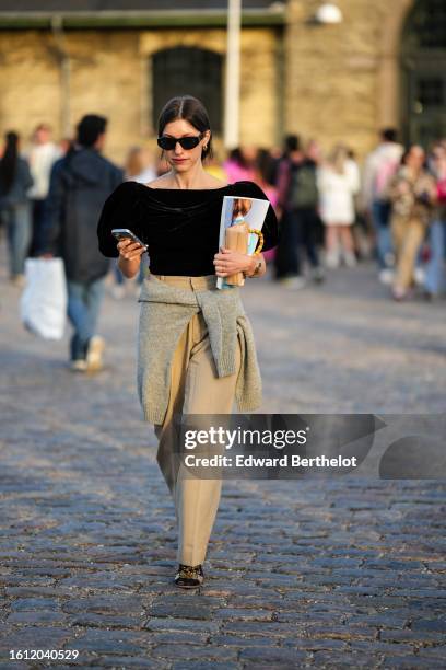 Guest wears black sunglasses, a white hair elastic, a black puffy short sleeves wool top, beige large suit pants, a pale gray wool pullover knot at...