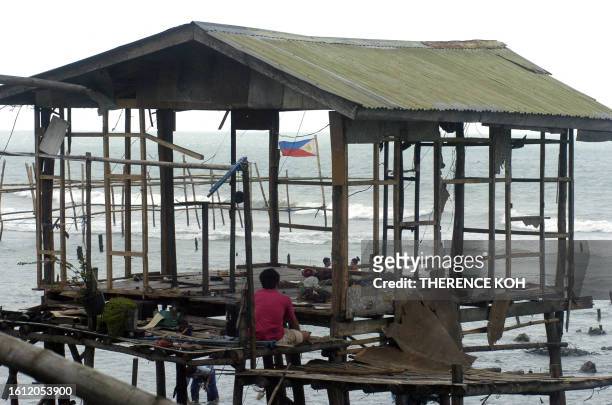 Resident looks at his housewhich was damaged by strong wind and waves in the coastal village of Zamboanga city in southern Philippines island of...