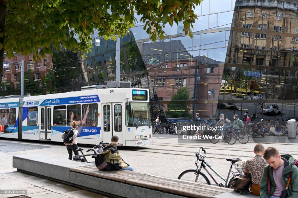 Moderne Architektur der Universitätsbibliothek Freiburg im Breisgau im Hintergrund eine Straßenbahn der Linie 5.