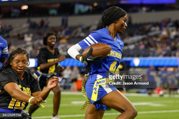 Inglewood, CA A player for for Crenshaw girls flag football runs the ball as they play King/Drew at halftime of the Rams and Raiders preseason game...