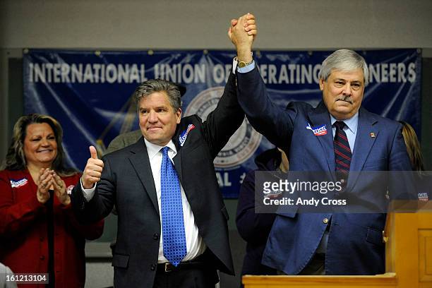 Denver Mayoral candidate, Chris Romer, left, and John Fleck, President of the Denver Area Labor Federation, right, join hands on stage at the...