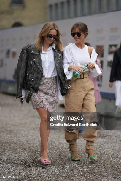 Guest wears black sunglasses, a white shirt, a black shiny leather zipper biker jacket, a beige and camel braided tweed wrap short skirt, pale pink...