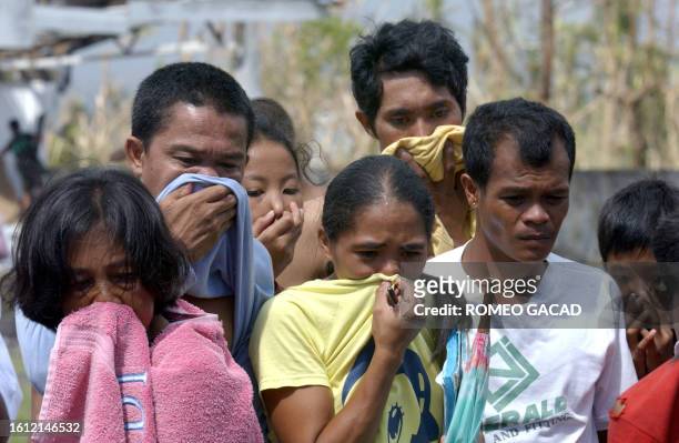 Villagers at an evacuation center in Padang, Legaspi city cover their noses to avoid the stench of decaying bodies as they try to identify a...