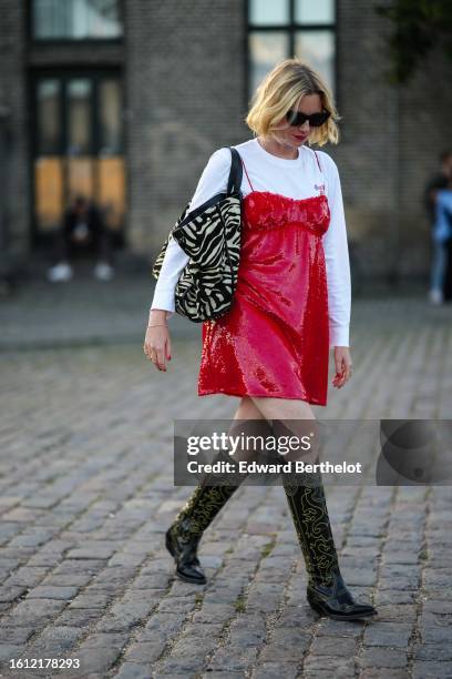 Guest wears black sunglasses, a white long sleeves t-shirt, a red shiny sequined shoulder-off short dress, a black and white zebra print pattern fur...