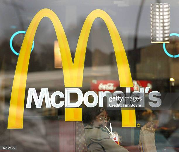 Patron is seen through a window displaying McDonald's golden arches as she eats her meal at a McDonald's restaurant November 11, 2002 in Willowbrook,...