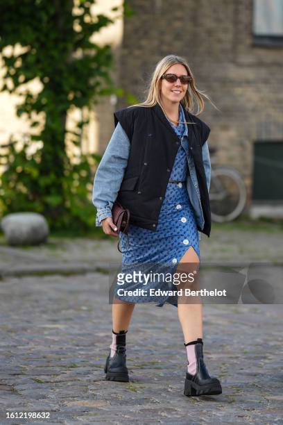 Guest wears black sunglasses, a black quilted shoulder pads / embroidered pale blue denim sleeves jacket, a blue denim shirt, a blue embroidered navy...