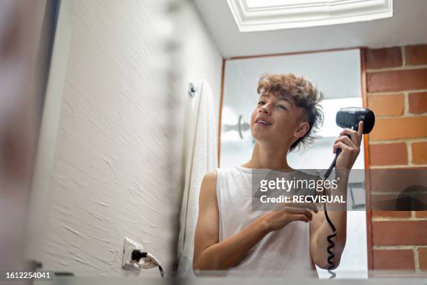 young teenage boy taking care of her skin and applying face mask at home. - blow drying hair stock pictures, royalty-free photos & images