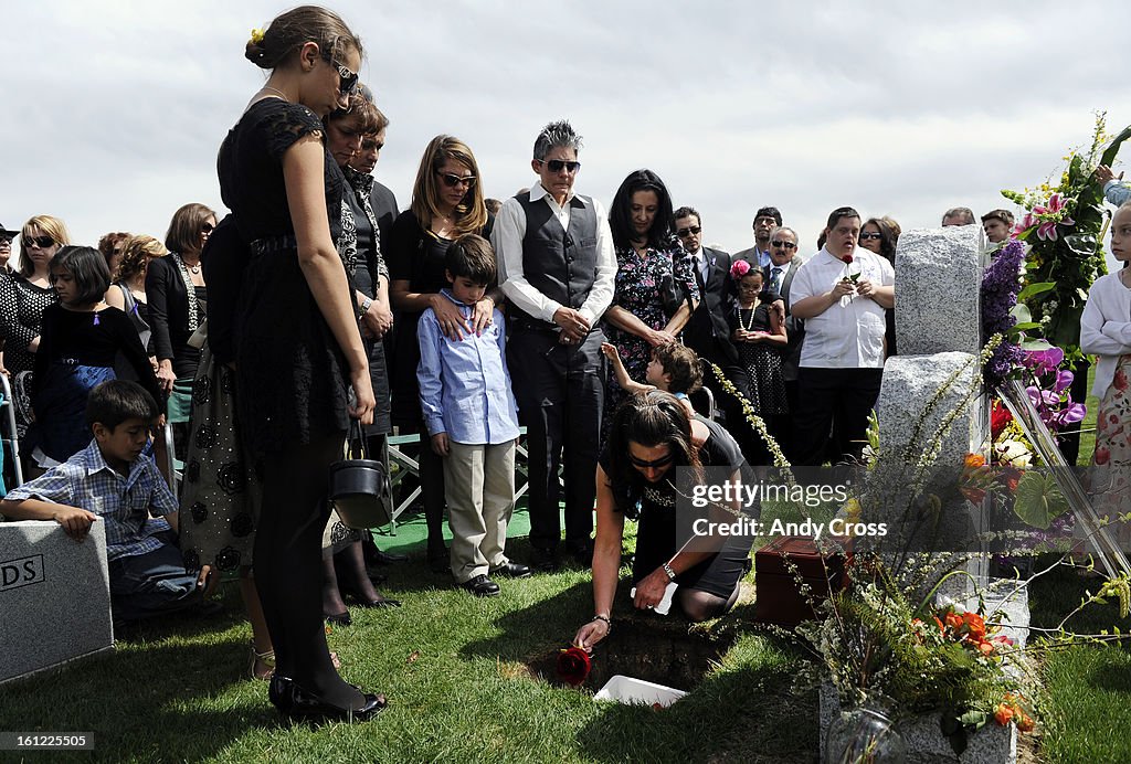 Andrea Sandoval Reed, surrounded by family and friends, places a rose inside her father's grave at Mt. Olivet Cemetery Saturday afternoon. Paul Sandoval, former Colorado State Senator, passed away April 24th, 2012 after a battle with pancreatic cancer. An