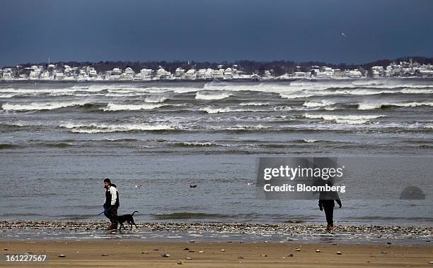 People walk along the beach after Winter Storm Nemo in Revere, Massachusetts, U.S., on Saturday, Feb. 9, 2013. More than two feet of snow fell on...