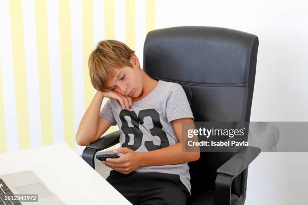 bored boy  using social media in mobile phone - addiction mobile and laptop stockfoto's en -beelden