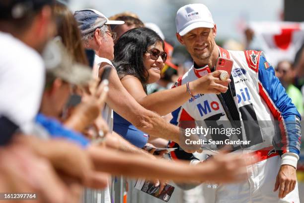 Jenson Button, driver of the Mobil 1 Ford, interacts with a NASCAR fan on the red carpet prior to the NASCAR Cup Series Verizon 200 at the Brickyard...