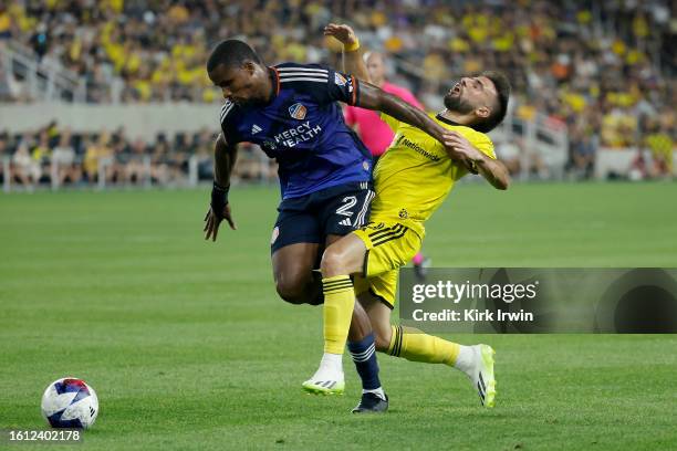 Diego Rossi of the Columbus Crew is knocked down by Alvas Powell of FC Cincinnati while chasing after the ball at Lower.com Field on August 20, 2023...