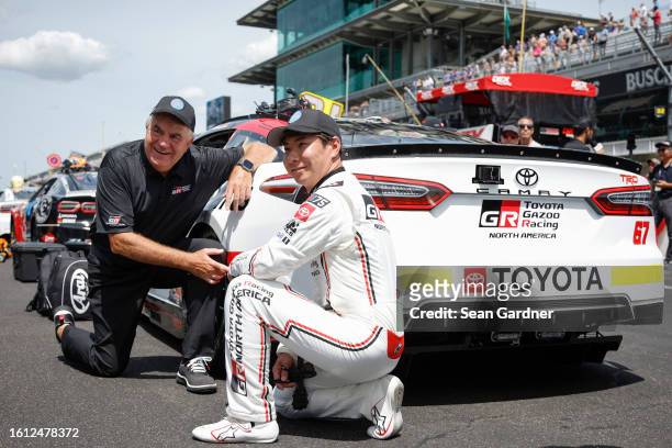 Kamui Kobayashi, driver of the Toyota Genuine Parts Toyota, poses on the grid prior to the NASCAR Cup Series Verizon 200 at the Brickyard at...
