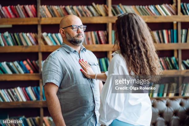 social phobia and healing therapy session. bald bearded man with eyes closed, in eyeglasses with woman hand on his chest in doctor office. woman rearview, focus on man - phobia stock pictures, royalty-free photos & images