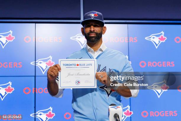 Former Toronto Blue Jay José Bautista holds his contract during a press conference after signing a one-day contract with the club, at Rogers Centre...