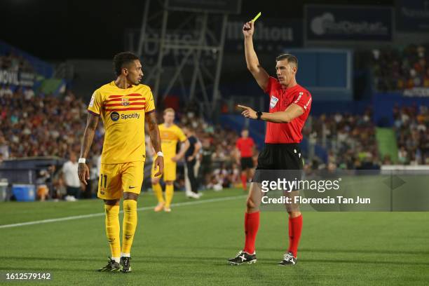 Match referee, Cesar Soto Grado, shows a yellow card to Raphinha of FC Barcelona during the LaLiga EA Sports match between Getafe CF and FC Barcelona...