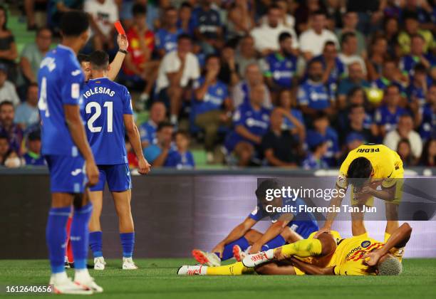 Ronald Araujo of FC Barcelona reacts holding his leg as match referee, Cesar Soto Grado, shows a red card to Jaime Mata of Getafe CF during the...