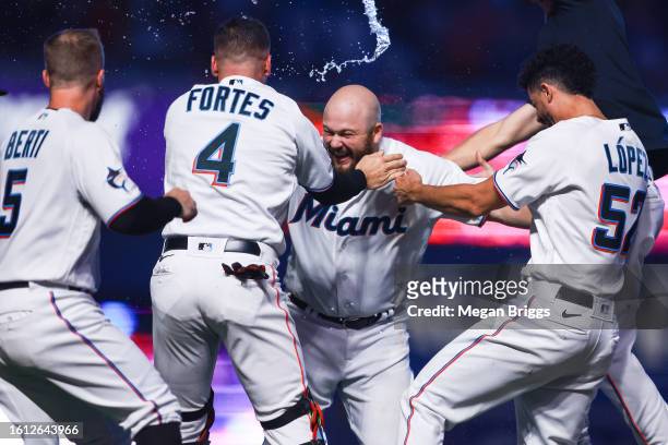 Jake Burger of the Miami Marlins celebrates with teammates after walking it off to defeat the New York Yankees at loanDepot park on August 13, 2023...