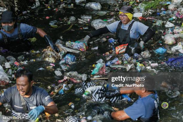 Environmental activists unclogs plastic trash on polluted river before being excavated for sorting and recycling in Denpasar, Bali, Indonesia on...