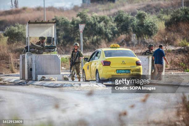 An Israeli soldier flicks a Palestinian man at a military checkpoint, during intensive operations to search for the attacker who shot at two Jewish...