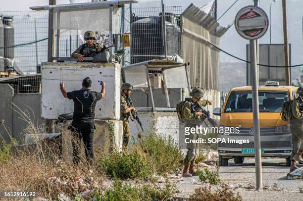 Palestinian man argues with Israeli soldiers after searching his car for a while and holding him at a military checkpoint during intensive operations...