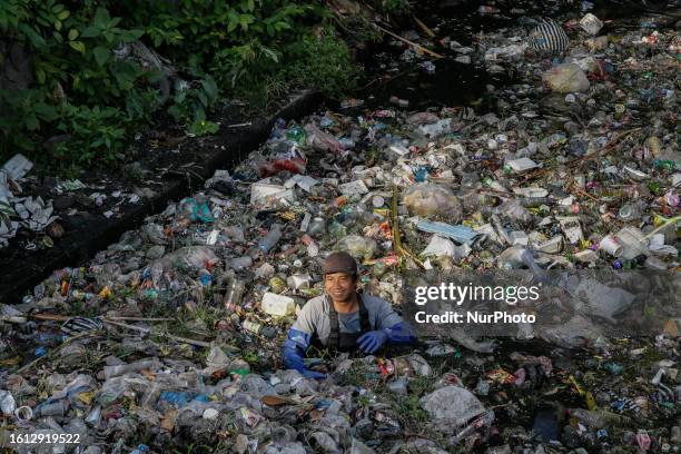 Environmental activists unclogs plastic trash on polluted river before being excavated for sorting and recycling in Denpasar, Bali, Indonesia on...