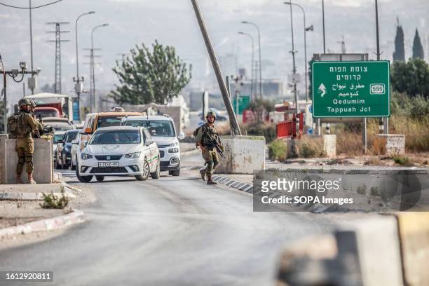 Israeli soldiers are seen guarding near a military post after closing the road during intensive operations to search for the attacker who shot at two...