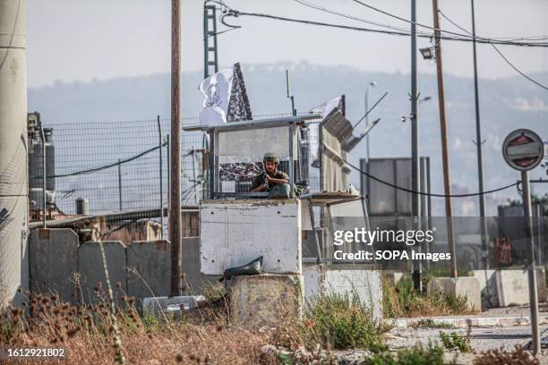 An Israeli soldier stands guard at a military post while others are searching vehicles passing near the area during intensive operations to search...