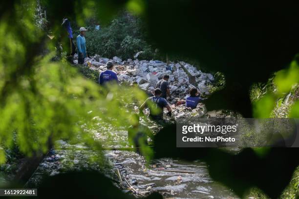 Environmental activists and government workers unclogs plastic trash on polluted river before being excavated for sorting and recycling in Denpasar,...